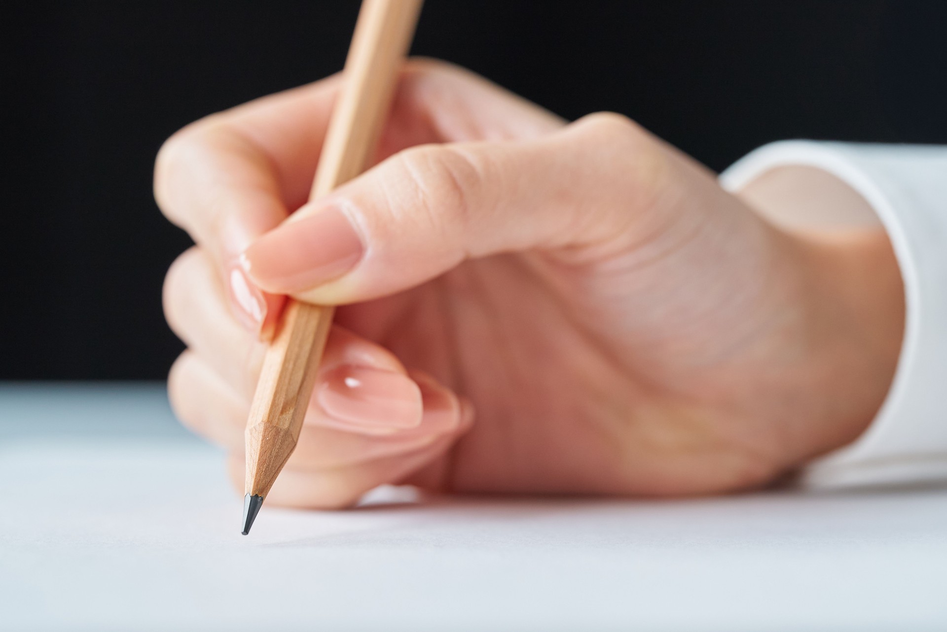 Hand holding a pencil and blank paper